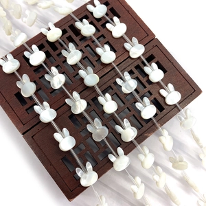 Natural pearl white shell rabbit shaped loose beads on a vintage wooden display tray