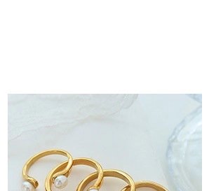 Nahaufnahme eleganter goldener Perlenringe mit Spiraldesign auf Marmorhintergrund