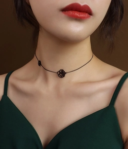 Detail showing a black cutout rose choker necklace on a model with elegant green attire