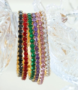 Detailed macro view of seven 18K gold plated tennis bracelets with colorful zircons