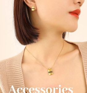 Détail d'une parure collier et boucles d'oreilles dorées à rayures noires sur mannequin