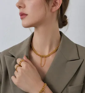 Primer plano de conjunto de collar y anillo de oro de 18k en modelo con chaqueta marrón