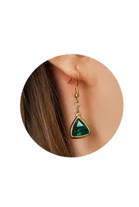 Detalle de pendientes dorados vintage con gema verde triangular y cierre de gancho