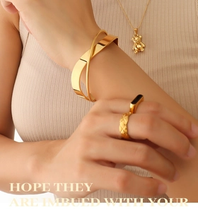 Detail of 18K gold-plated crossover bangle, bear pendant necklace and enamel rings set