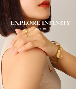 Detail of 18K gold-plated crossover bangle and ring set on model with soft lighting