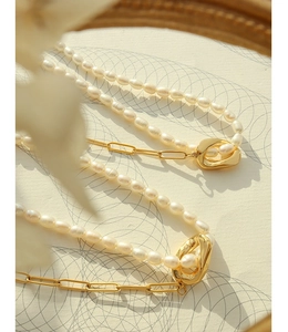 Detailed view of rice pearl necklace with golden paperclip chain and toggle clasp