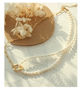 Detail of elegant double-layered gold paperclip chain necklace with freshwater pearls