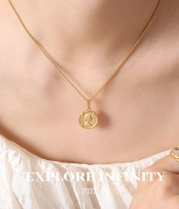 Gros plan d'un collier pendentif pièce dorée avec relief Reine Elizabeth II sur chaîne fine