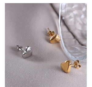 Detalle de pendientes en forma de corazón de acero de titanio pulido en oro y plata