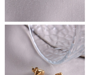 Primer plano de pendientes de titanio dorado con forma de corazón y flor elegante