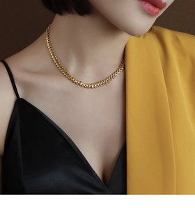 Detailopname van een stijlvolle goudkleurige bladketting gedragen door een model