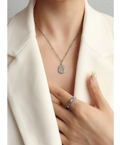 Primer plano detallado del collar con colgante Fu plateado y anillo en una modelo