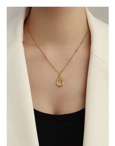 Detalle del collar de titanio bañado en oro de 18k con colgante Fu en el cuello