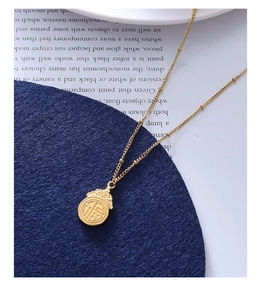 Detalle de un collar chapado en oro con colgante Fu en un soporte de terciopelo azul