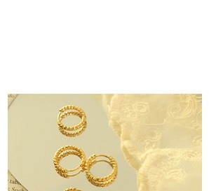 Vue rapprochée de boucles d'oreilles rondes plaquées or avec texture perlée