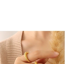 Détail d'une bague perlée dorée avec placage en or 18 carats sur le doigt du mannequin