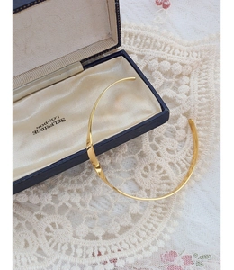 Gepolijste 18k gouden twist choker ketting op een elegante vintage kant achtergrond