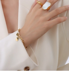 Dettaglio anello in titanio placcato oro 18K con inserto in conchiglia e bracciale cuore