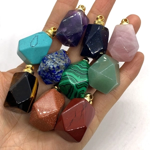 Assorted faceted gemstone pendants in various natural stones held in palm of hand
