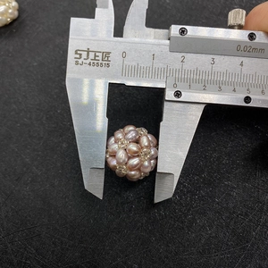 Macro shot measuring a 15mm lavender pearl beaded ball with a metal caliper tool