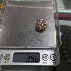 Close-up of a 3.96g handmade woven natural freshwater pearl ball on a digital scale