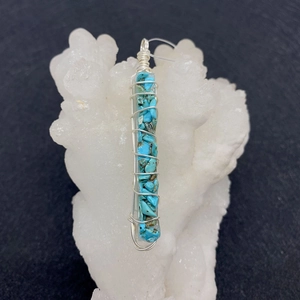 Macro view of blue natural stone chips in clear resin pendant with silver wire wrap