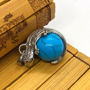 Macro detail of a silver lizard pendant featuring a round blue turquoise stone inlay
