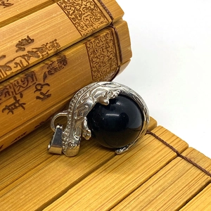 Detail of silver mythical beast clasp holding a large black stone on bamboo mat