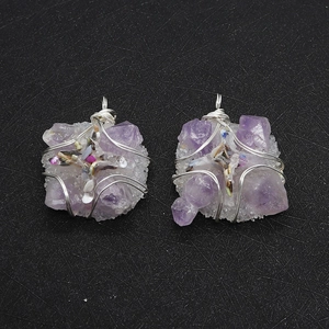 Detail of two handmade wire wrapped amethyst cross pendants with mixed crystal stones