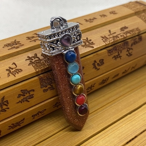 Makroaufnahme von Goldstein-Anhänger in Schwertform mit gravierter Kappe und 7 Chakra-Steinen