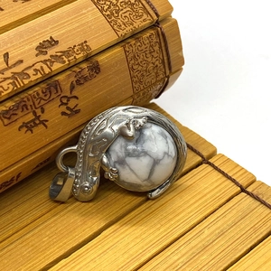 Detailed macro view of a silver lizard pendant with a natural round turquoise stone inlay