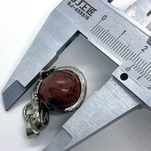 Macro view measuring a 12mm round mahogany obsidian gemstone pendant with silver claw setting