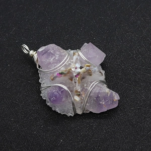 Macro shot of purple crystal cluster pendant with silver wire wrapping and shell details