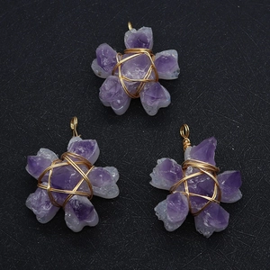 Macro detail of handmade wire wrapped purple amethyst flower pendants on black background
