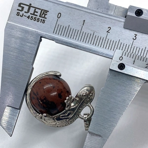 Lizard pendant measurement showing natural stone ball with silver claw setting via caliper