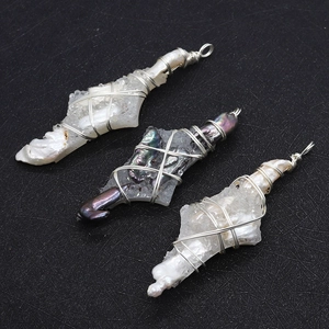 Macro detail of wire-wrapped baroque pearls and natural crystal pendants on black surface