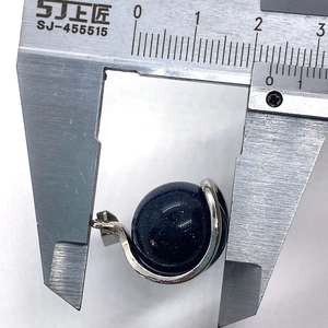 Vue macro mesurant le pendentif sphérique en grès bleu avec un pied à coulisse