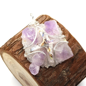 Handmade wire-wrapped lavender amethyst crystal pendant with pearl accents on a wood base
