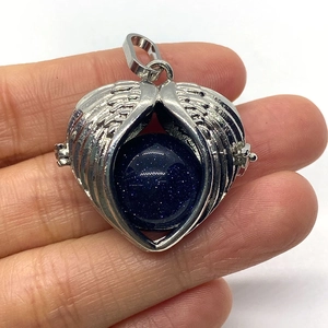Detail of opening silver heart wings pendant with blue starlight stone held in hand