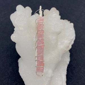Macro-opname van een handgemaakte roze natuurstenen hanger met zilveren draadwikkeling