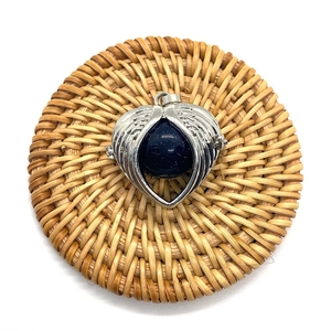 Silver angel wing heart pendant with blue sandstone bead on rustic rattan coaster
