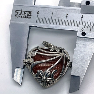 Measuring heart-shaped tiger eye pendant width with calipers showing 31mm size detail