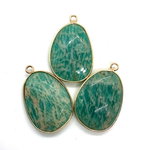 Close-up of three faceted teardrop natural stone pendants with gold-plated metal borders