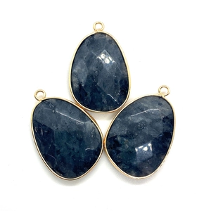 Close-up of faceted natural stone teardrop pendants with gold plated metal borders