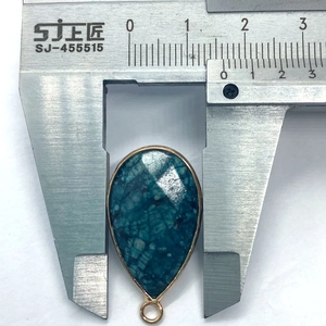 Gedetailleerde meting van een druppelvormige hanger van turquoise steen met gouden rand