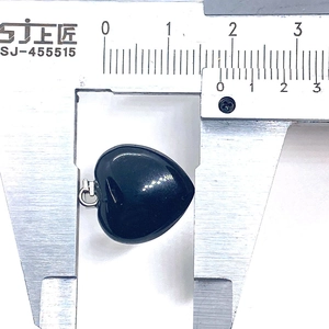Measuring heart-shaped black onyx pendant width with calipers showing 20mm size details