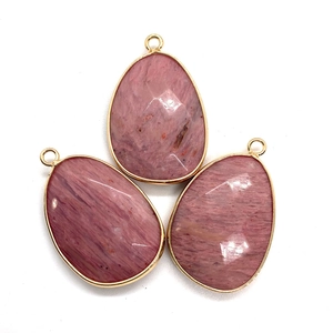 Three faceted teardrop pink natural stone pendants with gold metal edges on white background