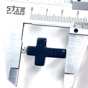 Detailed size measurement of a blue goldstone cross pendant with a digital caliper