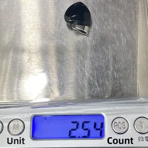 Makroaufnahme eines 2,54g herzförmigen Anhängers aus schwarzem Achat auf einer Waage