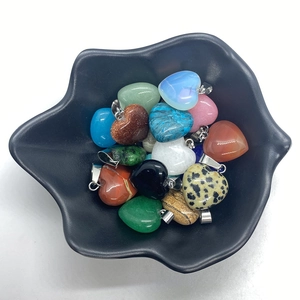Set of heart-shaped natural stone pendants with silver clasps on a black leaf-shaped dish